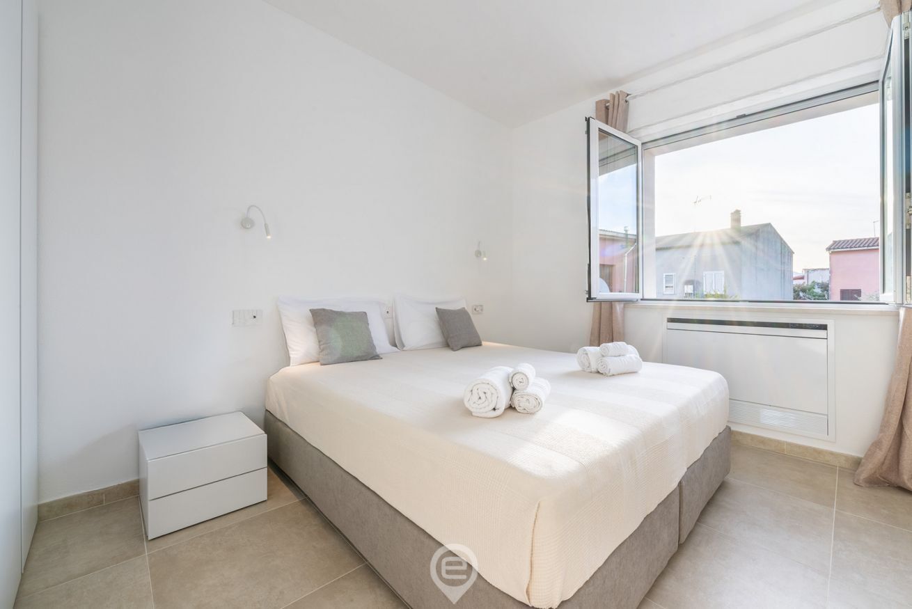 Een slaapkamer met een bed, een nachtkastje, een raam met uitzicht en een radiator.