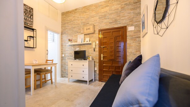 Un espace de vie compact comprenant un canapé, un téléviseur, une petite table et une chaise en bois.