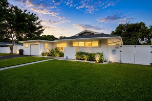 A two-story residential house with a well-maintained lawn, a garage, and a fenced backyard. - Your Own Private Luxe Resort – 12 Mins to Beach! (West Palm Beach)