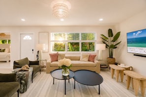 A modern living room with a sofa, coffee table, and a TV mounted on the wall. - Your Own Private Luxe Resort – 12 Mins to Beach! (West Palm Beach)
