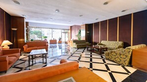 En lobby med et ternet gulv, flere sofaer, et sofabord og en lampe.