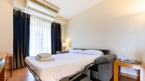 Et hotelværelse med en seng, et skrivebord og en stol.