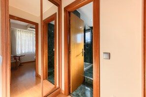 A hallway with wooden doors leading to a bathroom and a room with a toilet and a window with curtains. - M (MLE16A2320) Expanded bedroom 1 bedroom in Chamartín (Madrid)