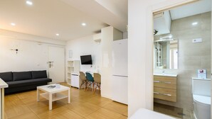 Een moderne woonkamer met een bank, salontafel en een aan de muur bevestigde televisie.
