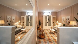 Een ruime woonkamer met een bank, twee fauteuils, een salontafel en een vloerkleed met een patroon.