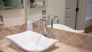 A bathroom with a white sink, a mirror, and a tiled wall.