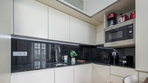 Une cuisine moderne avec un plan de travail noir, un évier en acier inoxydable et des armoires blanches.