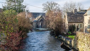 A narrow waterway flanked by stone walls and vegetation, leading to a traditional stone building with a gabled roof. - Filly Island - sleeps 2 guests  in 1 bedroom (South Cerney)