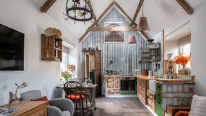 A rustic kitchen with exposed beams, a wooden dining area, and a view into the adjacent room. - Filly Island - sleeps 2 guests  in 1 bedroom (South Cerney)