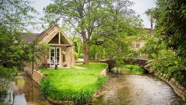 A stone cottage with a thatched roof, a small garden, and a narrow waterway with a bridge. - Filly Island - sleeps 2 guests  in 1 bedroom (South Cerney)