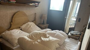 A bedroom with a wooden bed, white bedding, a nightstand with a lamp, and a window with curtains. - Complete Winterberg residence Fichtenweg 54, near the slopes and Bikepark. (Winterberg)