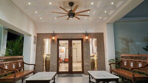 A hotel lobby with a ceiling fan, two wooden benches, a marble table, and a door leading to another room. - 7 BHK villa with Private pool near Siolim and Anjuna (Siolim)