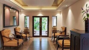 A hotel lobby with a reception desk, seating area, and large glass doors leading to an outdoor space. - 7 BHK villa with Private pool near Siolim and Anjuna (Siolim)