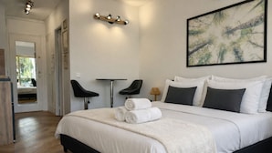 A modern bedroom with a large bed, two black chairs, a small table, and a painting on the wall. - Marina - Magnifique Appartement - Exclusive (Villeneuve-Loubet)