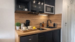 A modern kitchen with black cabinets, a stainless steel microwave, a coffee maker, and a sink. - Marina - Magnifique Appartement - Exclusive (Villeneuve-Loubet)