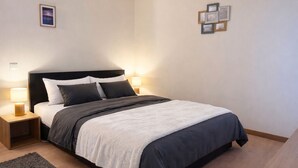 Ein modernes Schlafzimmer mit einem großen Bett, zwei Nachttischen und einem Beistelltisch.