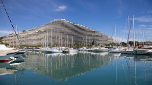 Ein großes Kreuzfahrtschiff liegt in einer Marina vor Anker, wo mehrere Segelboote liegen.