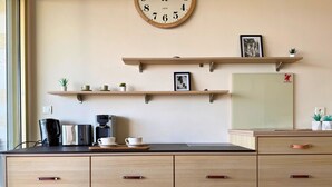 Eine Küche mit Holzausstattung, einer Kaffeemaschine und einer Uhr an der Wand.