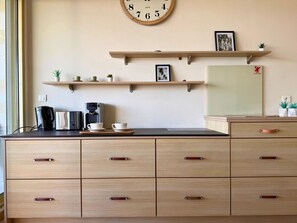 A kitchen with wooden cabinets, a coffee maker, and a clock on the wall. - Marina vue mer panoramique- Premium (Villeneuve-Loubet)