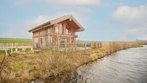 Ein rustikales Blockhaus an einem Fluss, eingebettet in eine natürliche Landschaft.