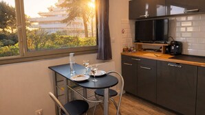 A compact kitchen with a dining table, chairs, a TV, and a view of the outside. - Studio - marina sea view- smart (Villeneuve-Loubet)