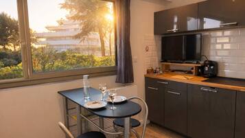 A compact kitchen with a dining table, chairs, a TV, and a view of the outside.
