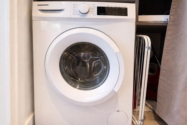 A front-loading white washing machine with a control panel and a transparent door. - Studio - marina sea view- smart (Villeneuve-Loubet)
