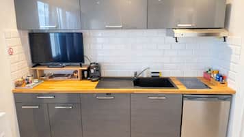 A modern kitchen with grey cabinets, a black countertop, a built-in stove, a sink, and a dishwasher.