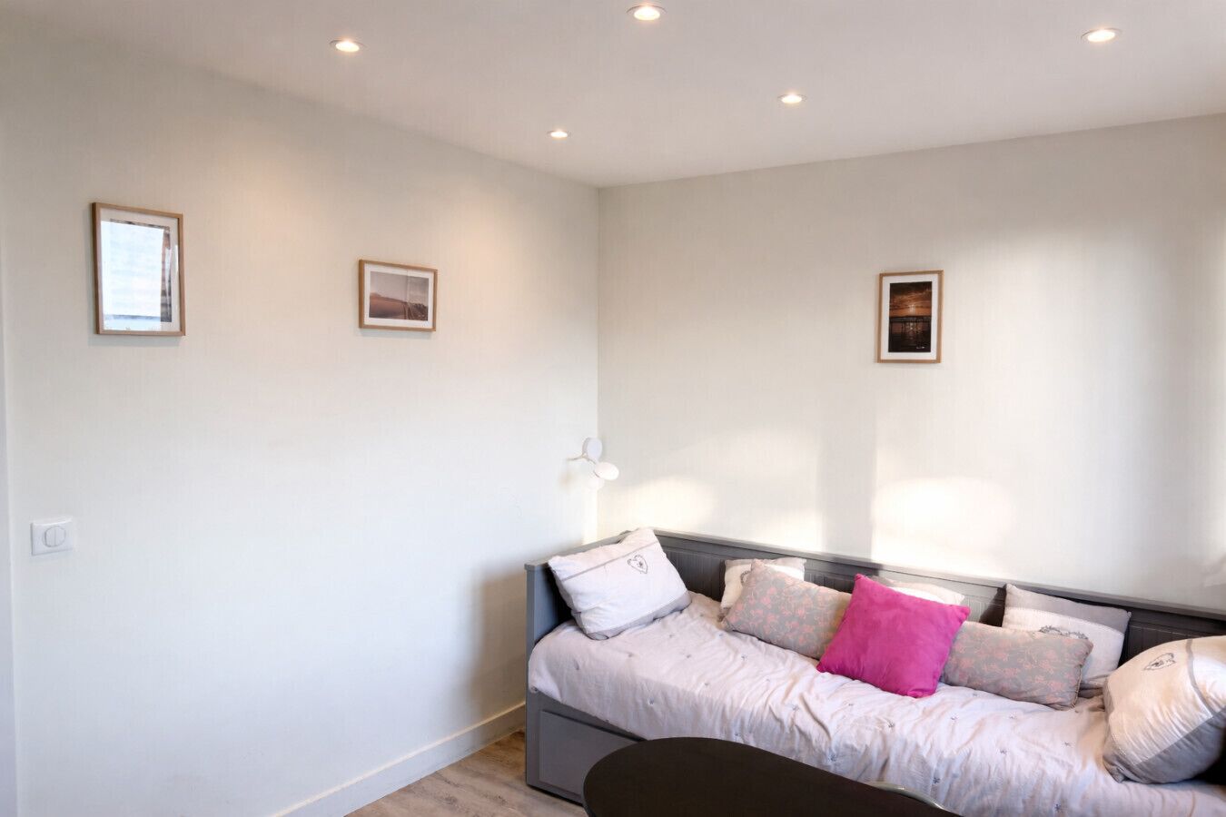 A bedroom with a bed, a bedside table, and a wall-mounted lamp.