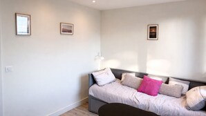 A bedroom with a bed, a bedside table, and a wall-mounted lamp. - Studio - marina sea view- smart (Villeneuve-Loubet)