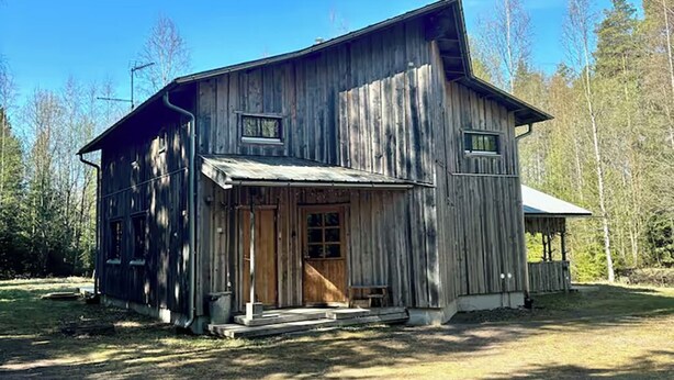 Tunnelmallinen, maalaishenkinen puumökki, jossa on kuisti, suuret ikkunat ja savupiippu.