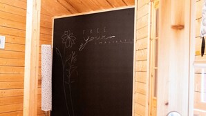 Puinen sisustus, jossa on liitutaulu, johon on kirjoitettu teksti: ”PÄÄSTÄ KUVITUKSEESI VALLAT” ja jossa on lisäksi kukkakuvioita.