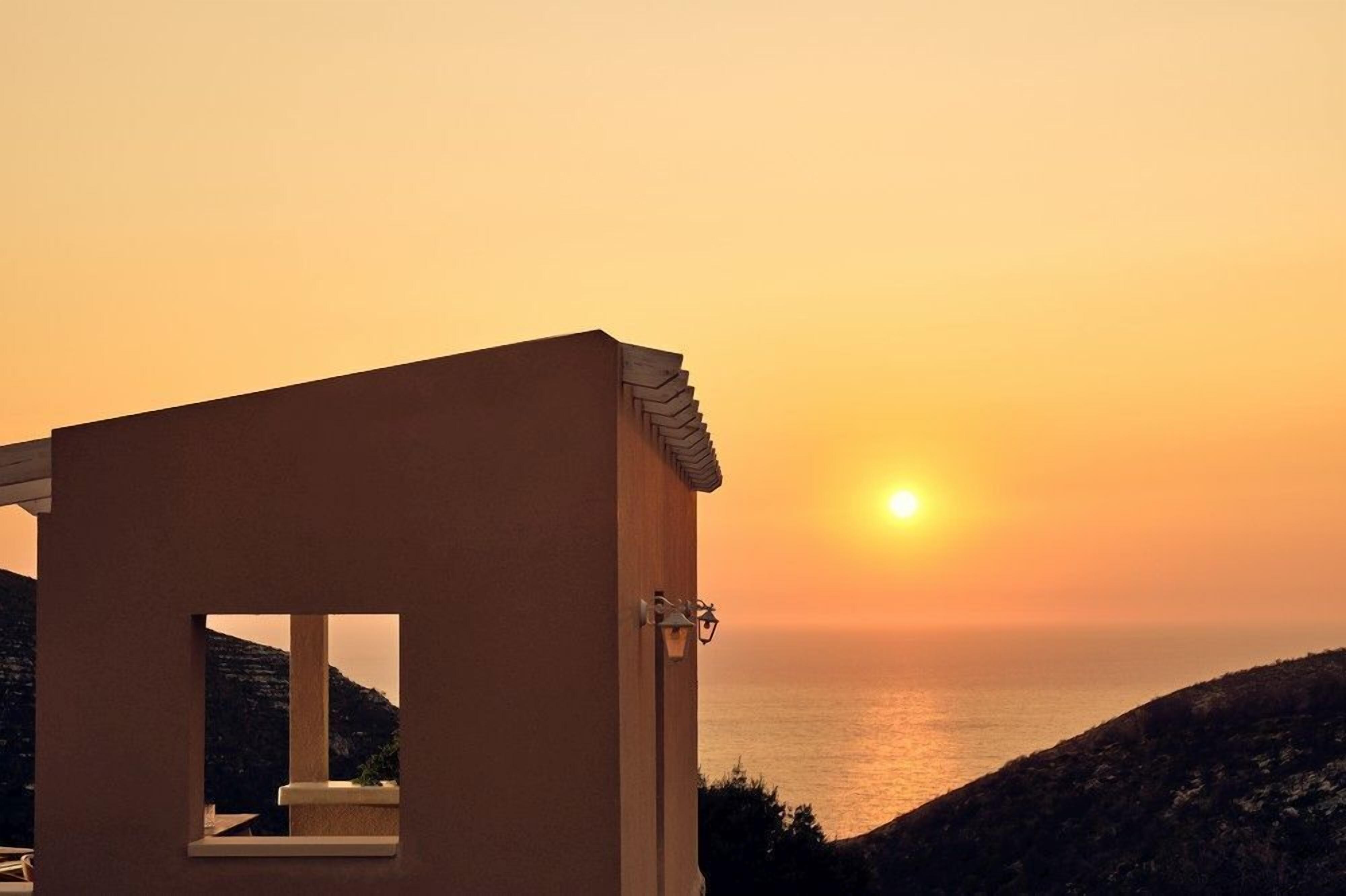 A building with a window overlooking a sunset over the sea.