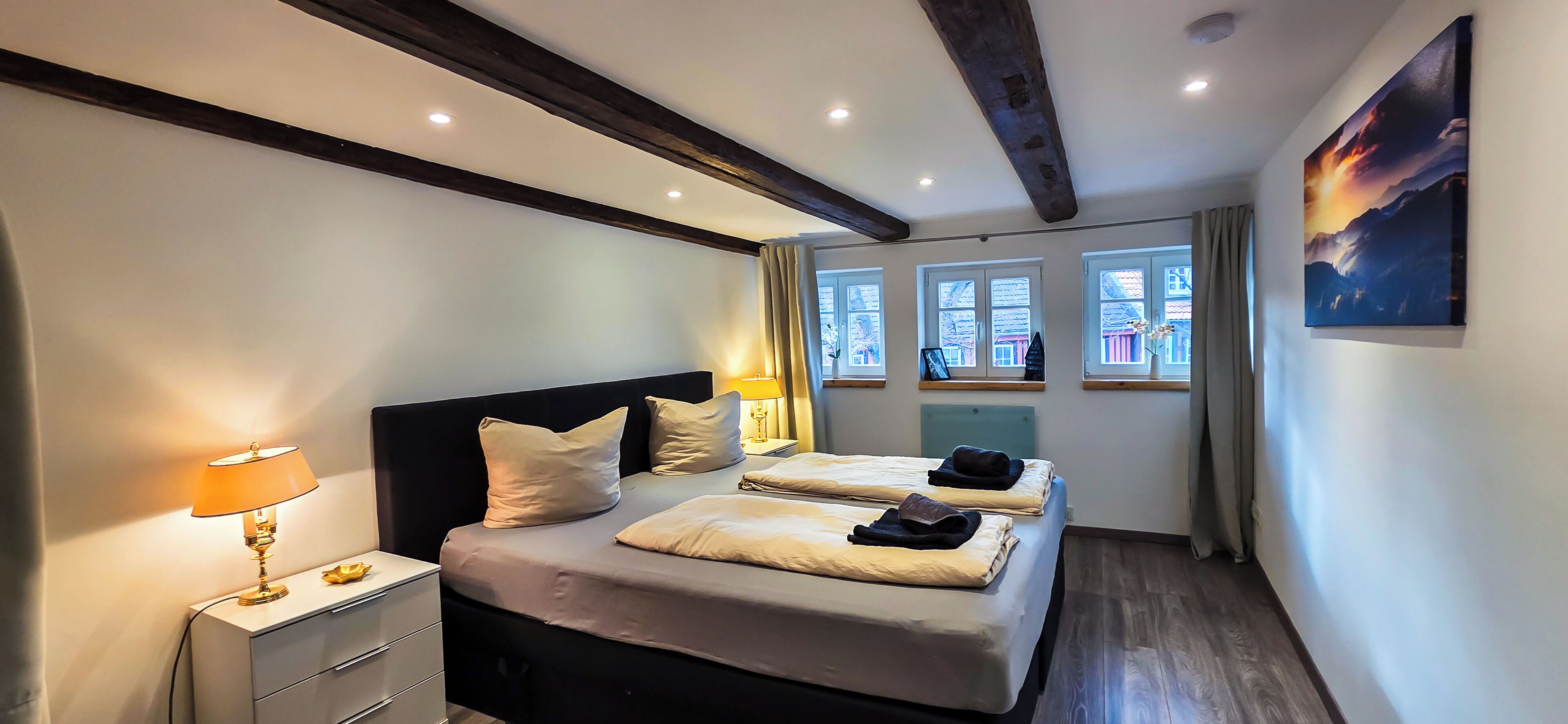 Une chambre à coucher avec un lit, des tables de chevet, une lampe et une fenêtre avec des rideaux.