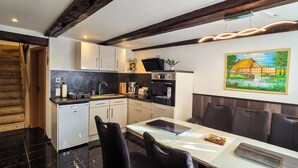 Una cocina moderna con armarios blancos, encimera negra y zona de comedor con mesa y sillas.