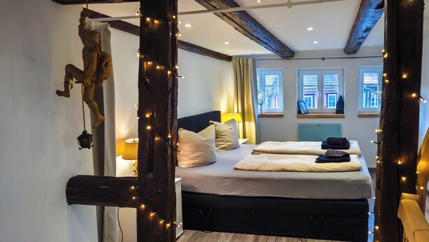 Un dormitorio acogedor con cama, lámpara de noche y vistas al exterior a través de ventanas.
