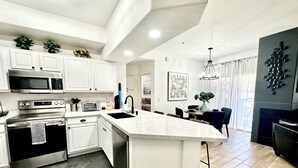 A modern kitchen with white cabinetry, stainless steel appliances, and a large island. - Modern Resort Escape (Tempe)