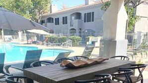An outdoor patio area with a pool, lounge chairs, and a dining table with chairs. - Modern Resort Escape (Tempe)