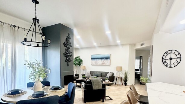 A modern living room with a dining area, featuring a chandelier, a sofa set, and a large clock on the wall. - Modern Resort Escape (Tempe)
