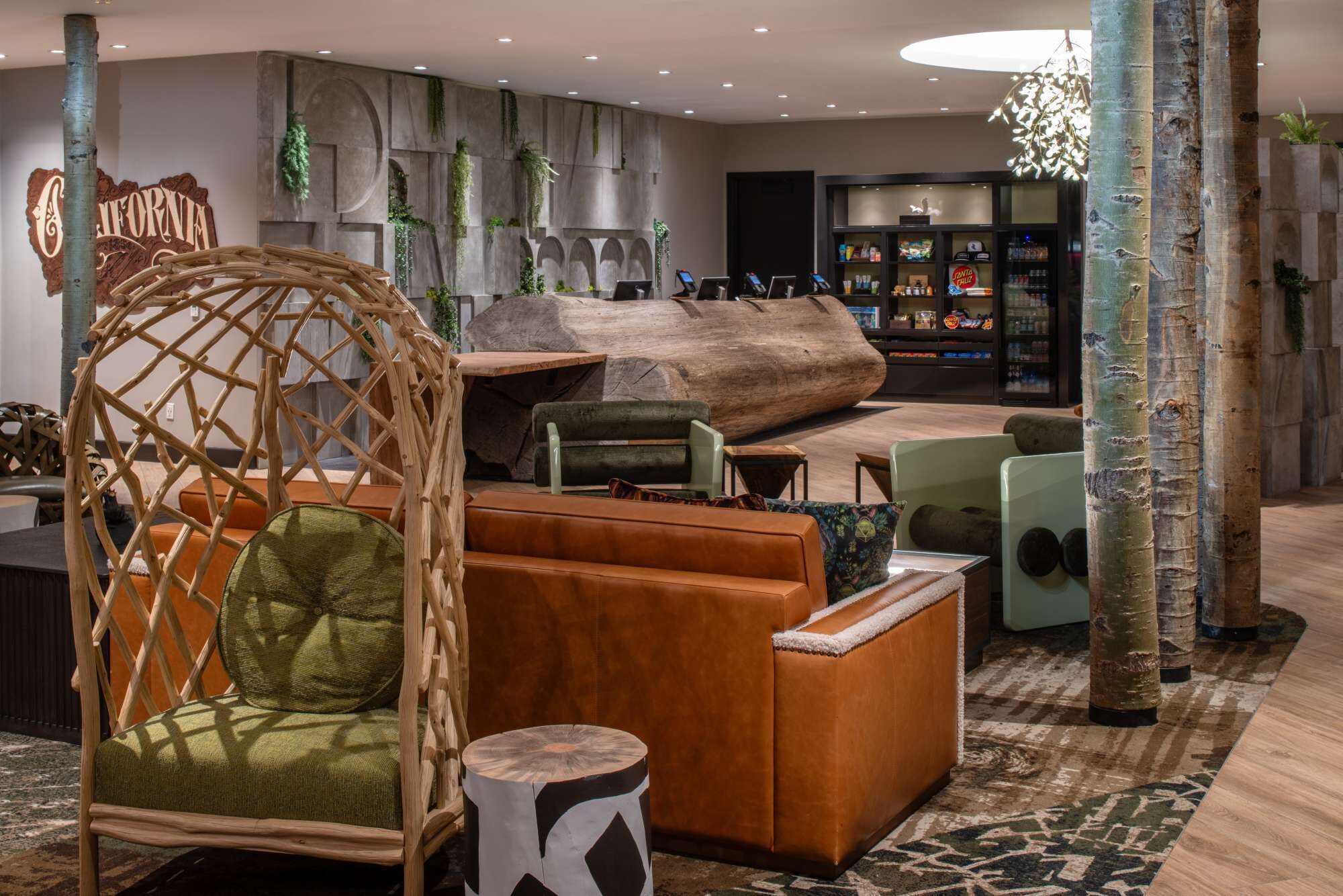 A modern lounge area with a large wooden sculpture, cushioned seating, and a bar area with a refrigerator.