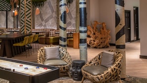 Un espace détente avec un baby-foot, des fauteuils en osier et un bar avec des sièges.