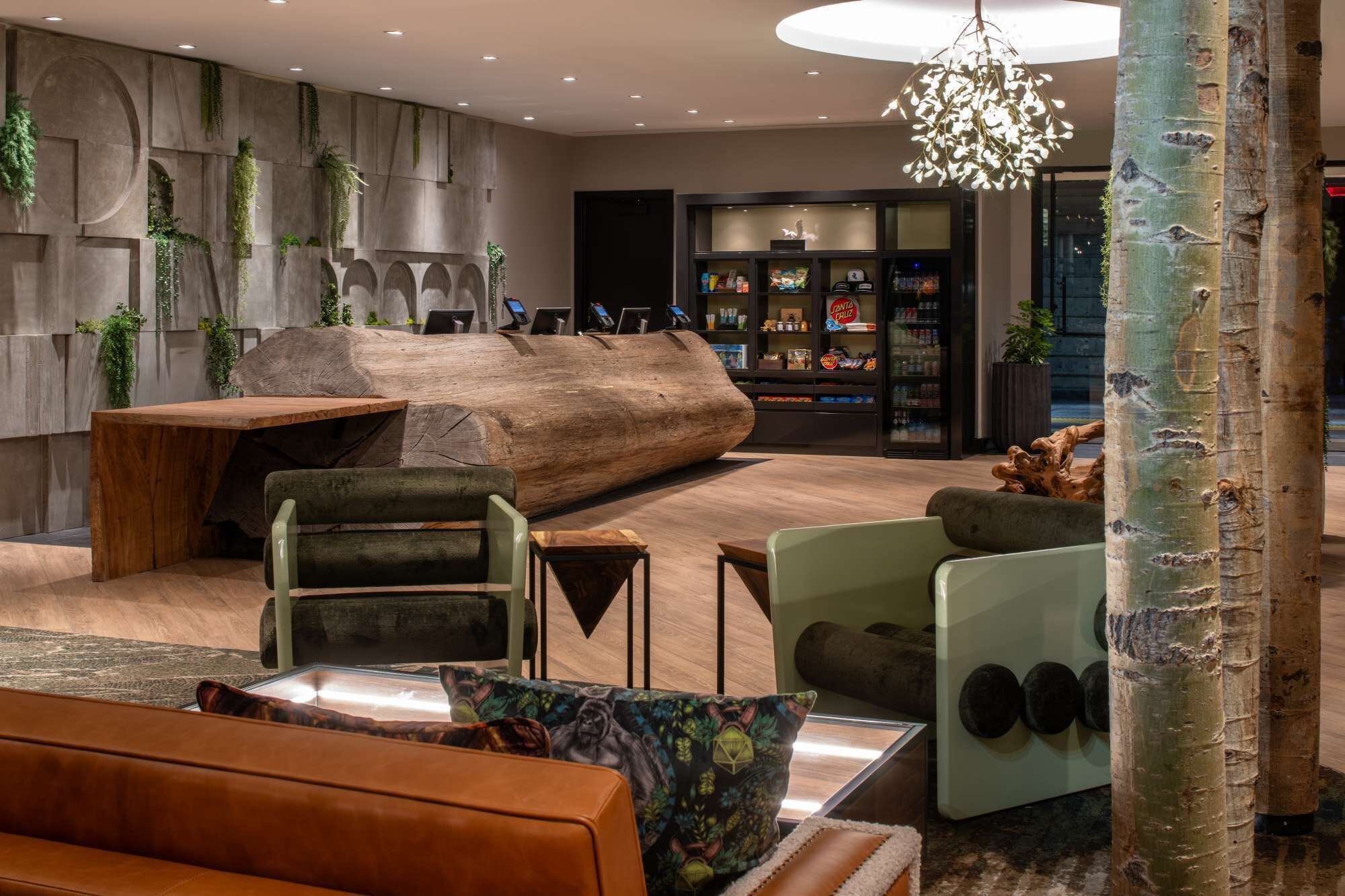 A modern lounge area with a large wooden log centerpiece, seating arrangements, and a display case with snacks.