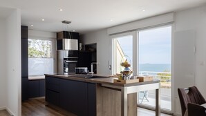 Eine moderne Küche mit einer großen Kochinsel, integrierten Geräten und Blick aufs Meer.