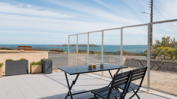 Une terrasse avec une table et des chaises, offrant une vue sur la côte.
