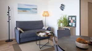 Un salon moderne avec un canapé, une table basse, une lampe, une horloge murale et un tableau encadré.