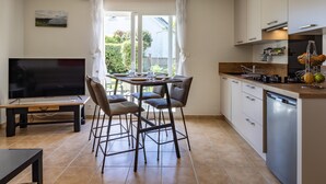 Une cuisine moderne avec un coin repas, un téléviseur et une vue sur l’extérieur.