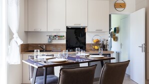 Une cuisine moderne avec des meubles blancs, une cuisinière noire et une table à manger accompagnée de chaises.