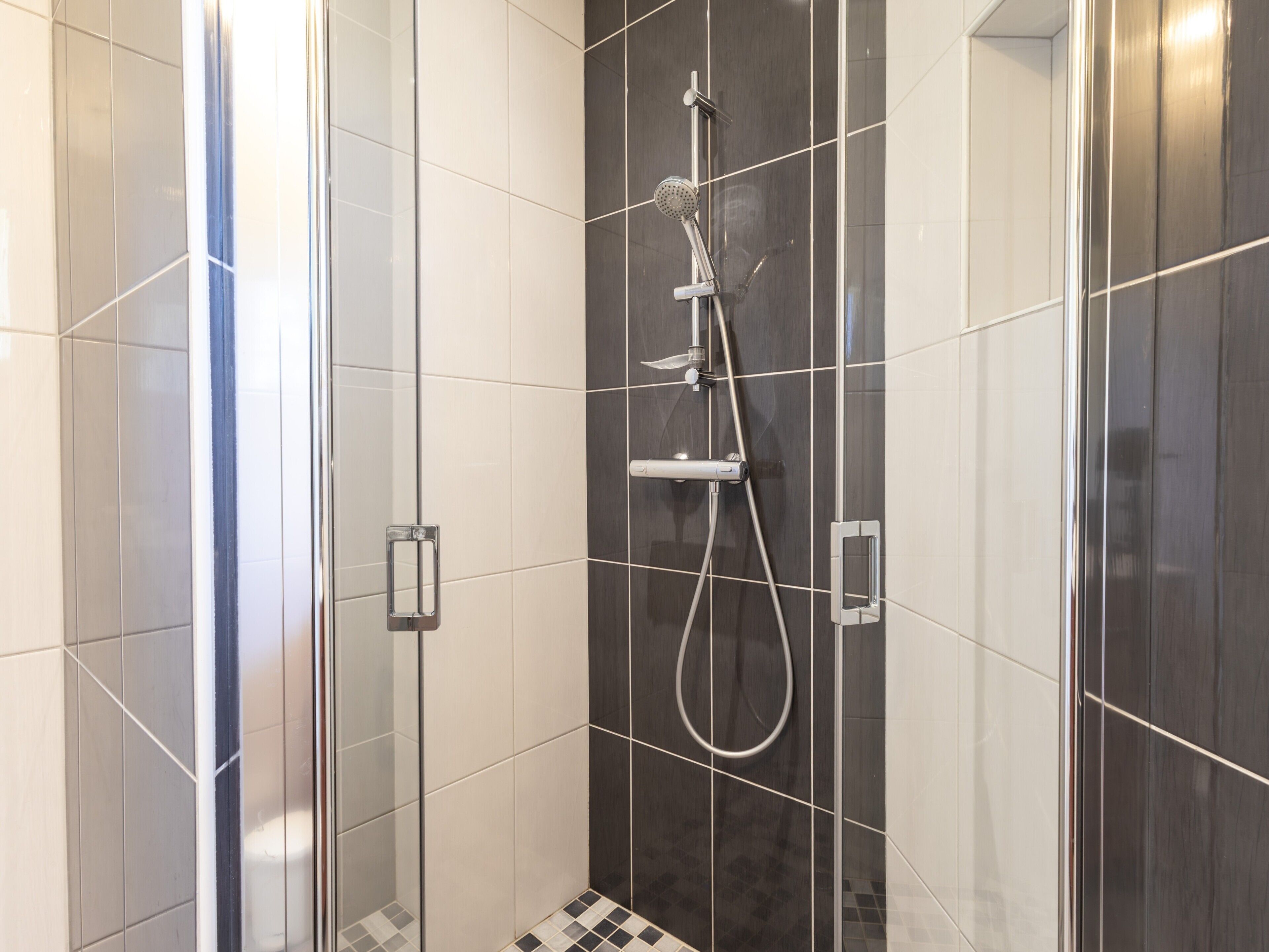Eine moderne Duschkabine mit Handbrause und Wandarmatur.