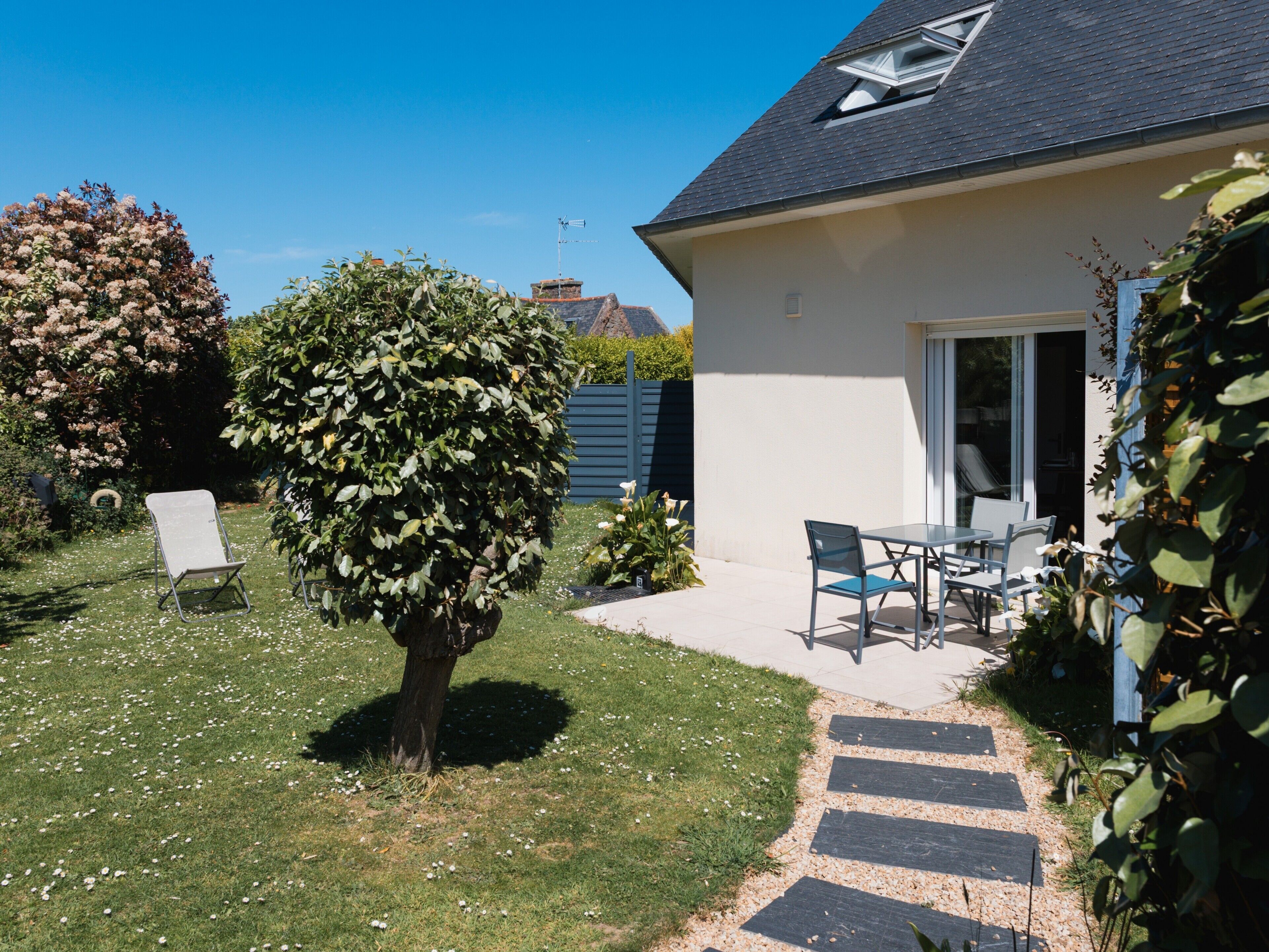 Een huis met een terras, gazon en een boom.
