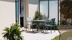 Une terrasse extérieure avec une table et des chaises, une porte et une antenne parabolique.